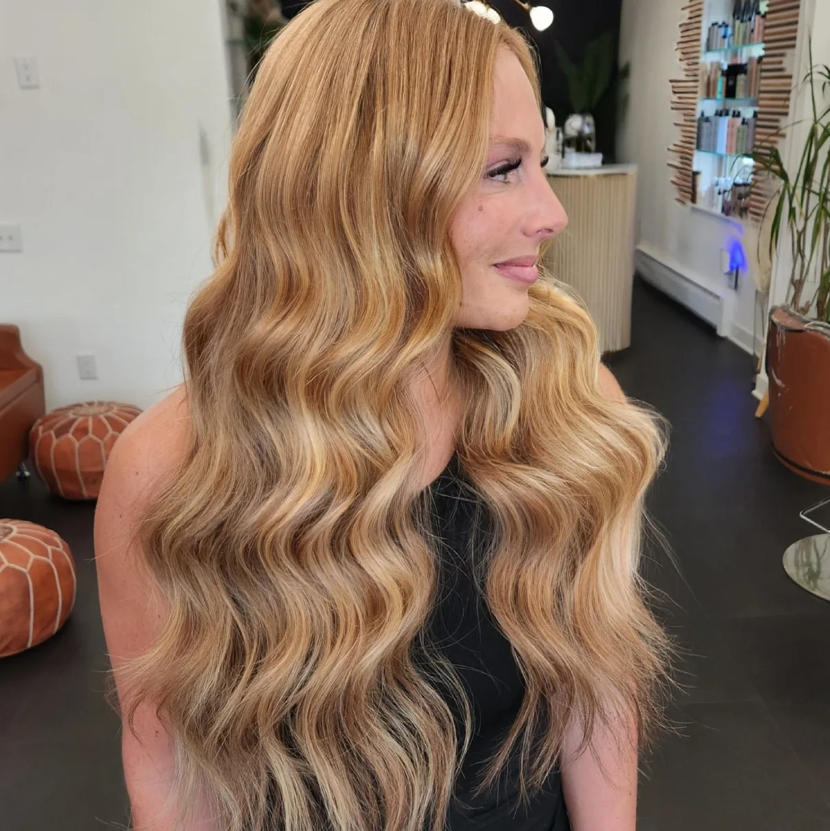 A warm golden blonde colour melt in long waves, photographed on the salon floor.